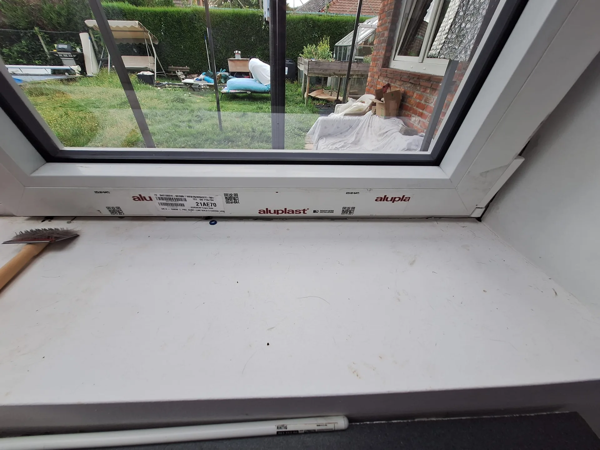Gemonteerde raam Aluplast met witte binnenvensterbank, detail parapetwerk
