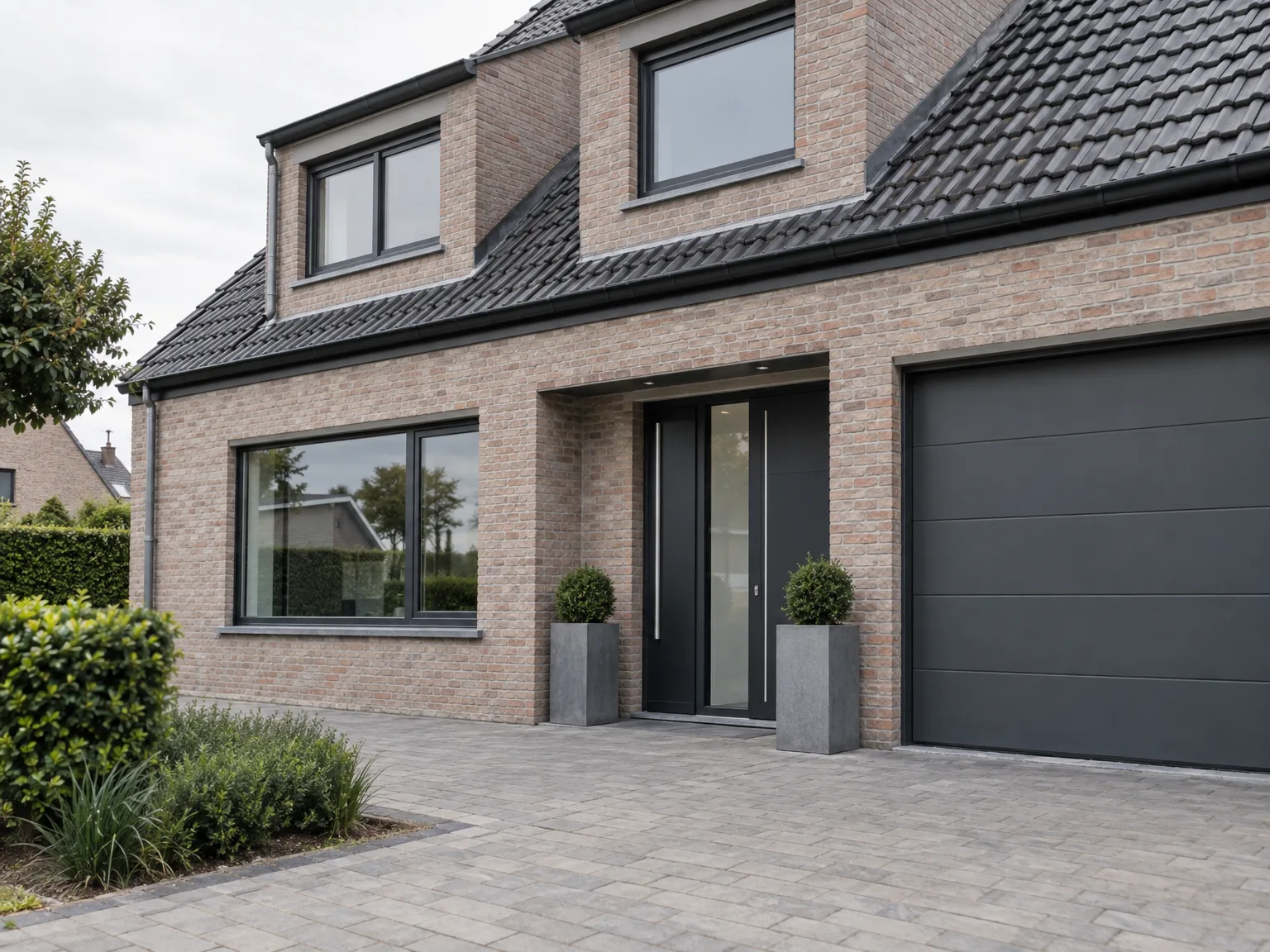 Nieuwbouw met bakstenen gevel, grote ramen in zwarte kozijnen, voordeur en garagedeur