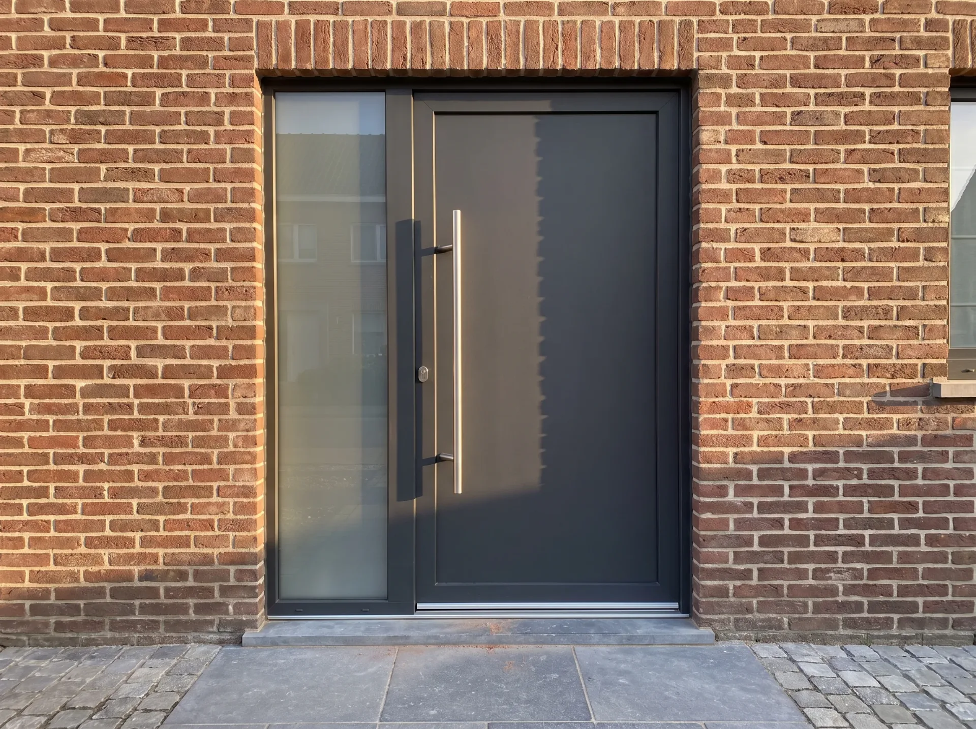 Zwarte aluminium schuifdeur met bovenlicht in bakstenen gevel