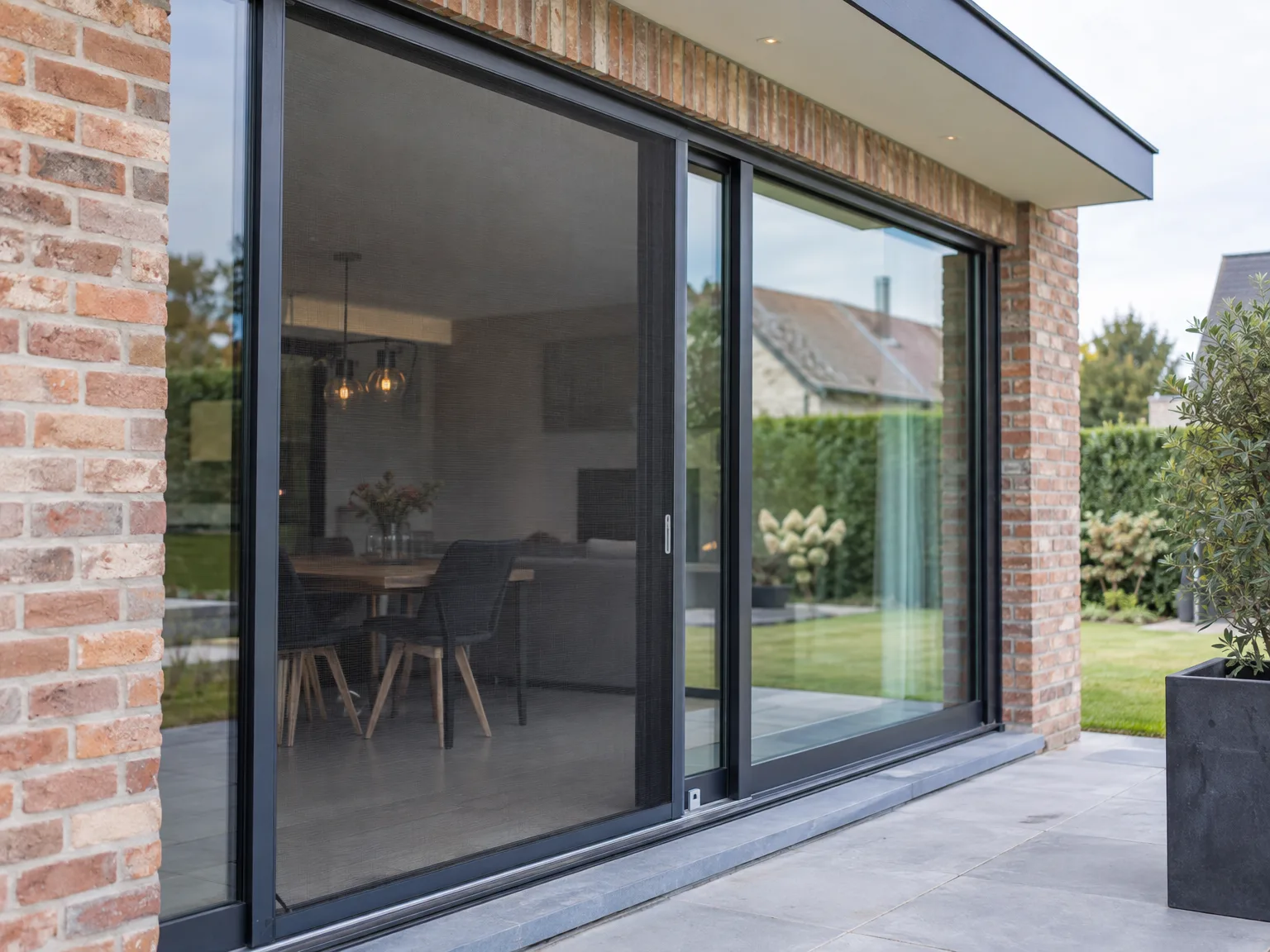 Schuiframen in zwart aluminium in modern woonhuis, uitzicht op tuin en interieur