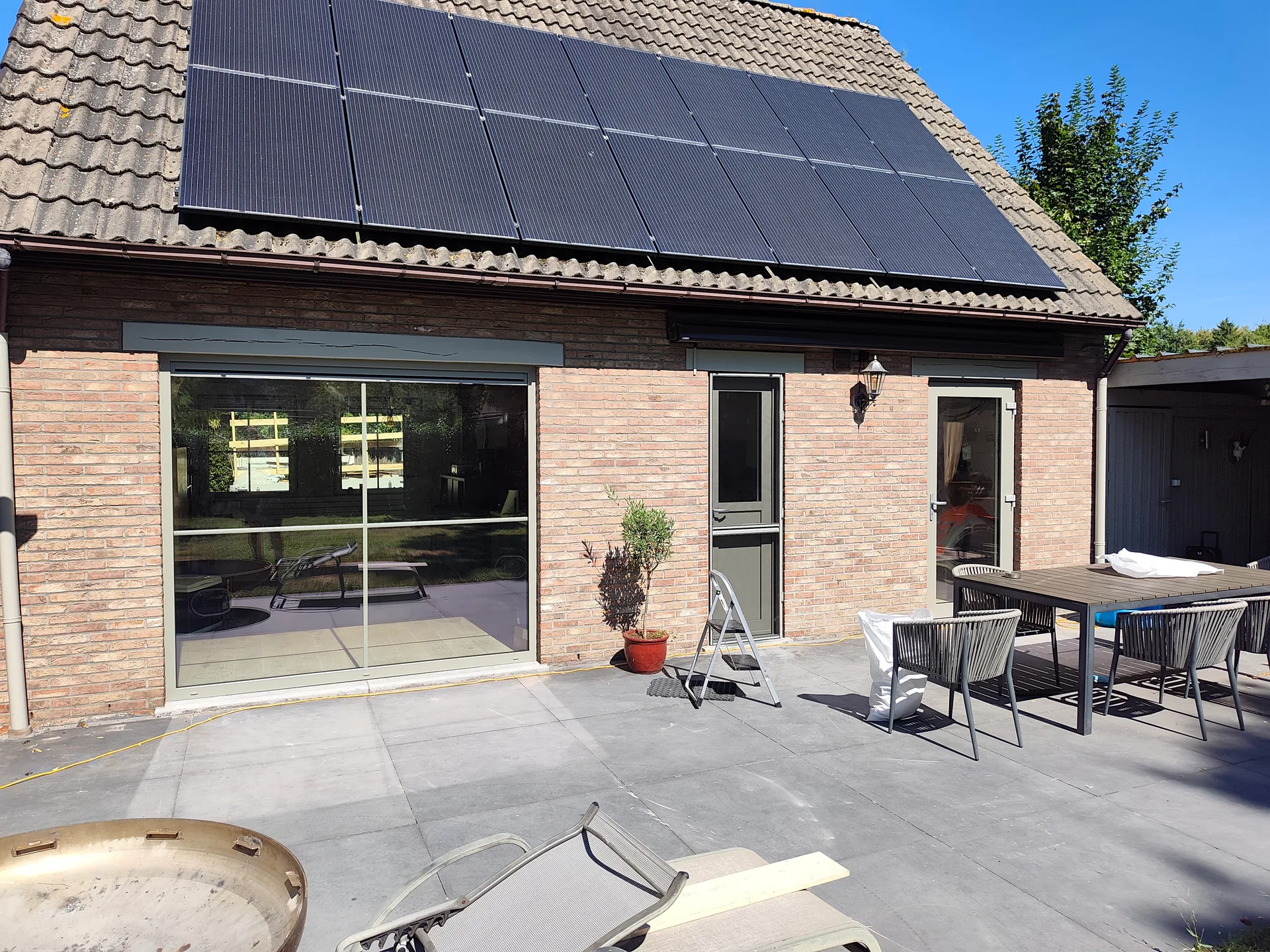 Grote schuiframen in bakstenen woning met helder zicht op interieur en terras