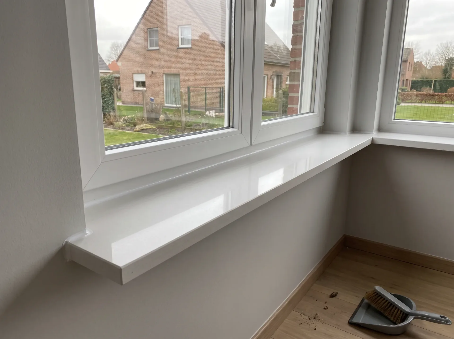 Witte binnenvensterbanken onder moderne PVC-ramen met tuinzicht